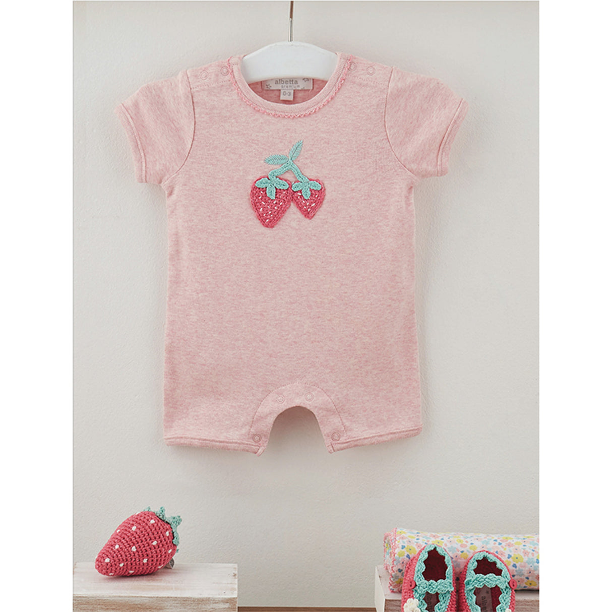Pink baby romper with strawberry design and strawberry rattle