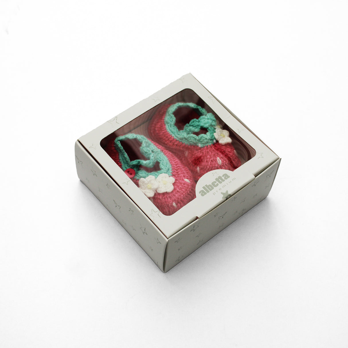 Pair of strawberry pink and green baby booties in a box on a white background