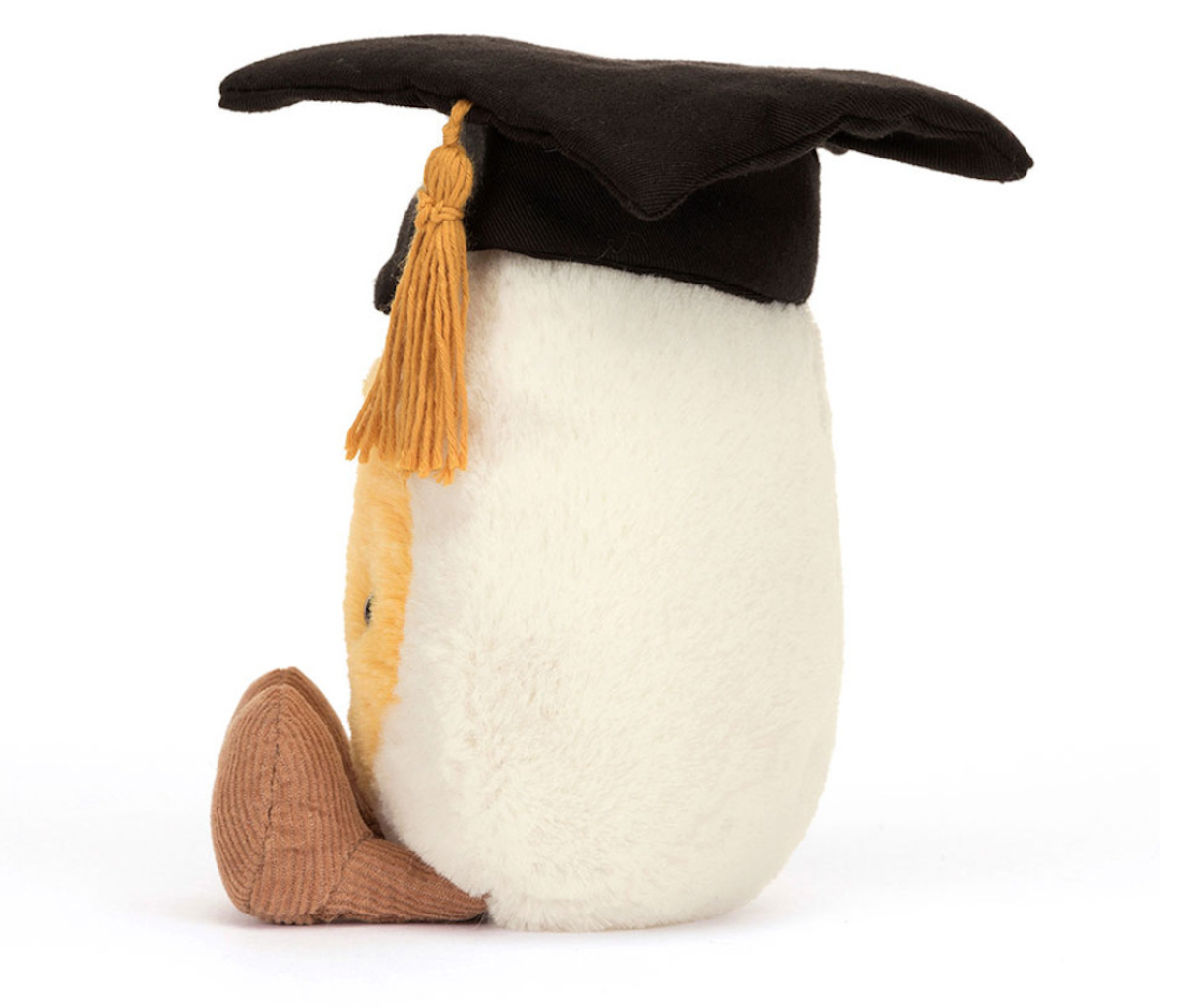 A plush toy resembling a smiling boiled egg wearing a black graduation cap with a golden tassel.