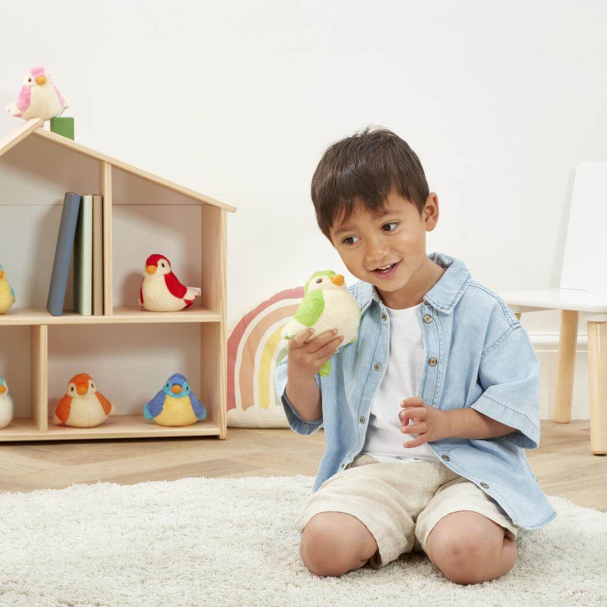 Child holding a toy bird in a room with shelves and toys