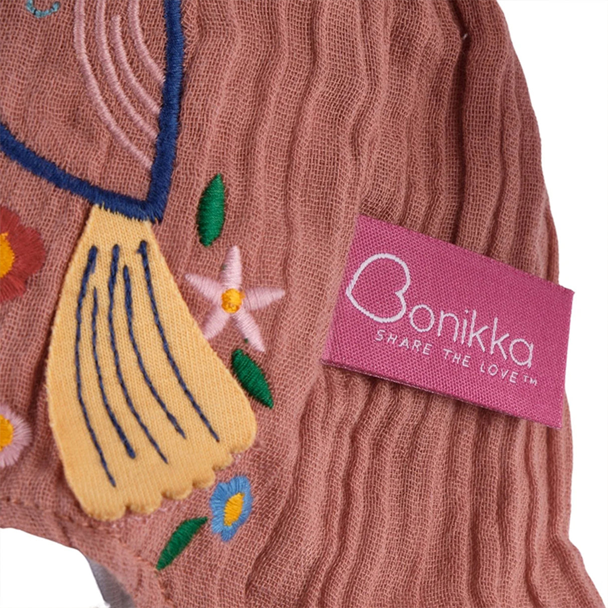 Close-up of a pink dress with floral designs and a pink 'Bonikka' label.