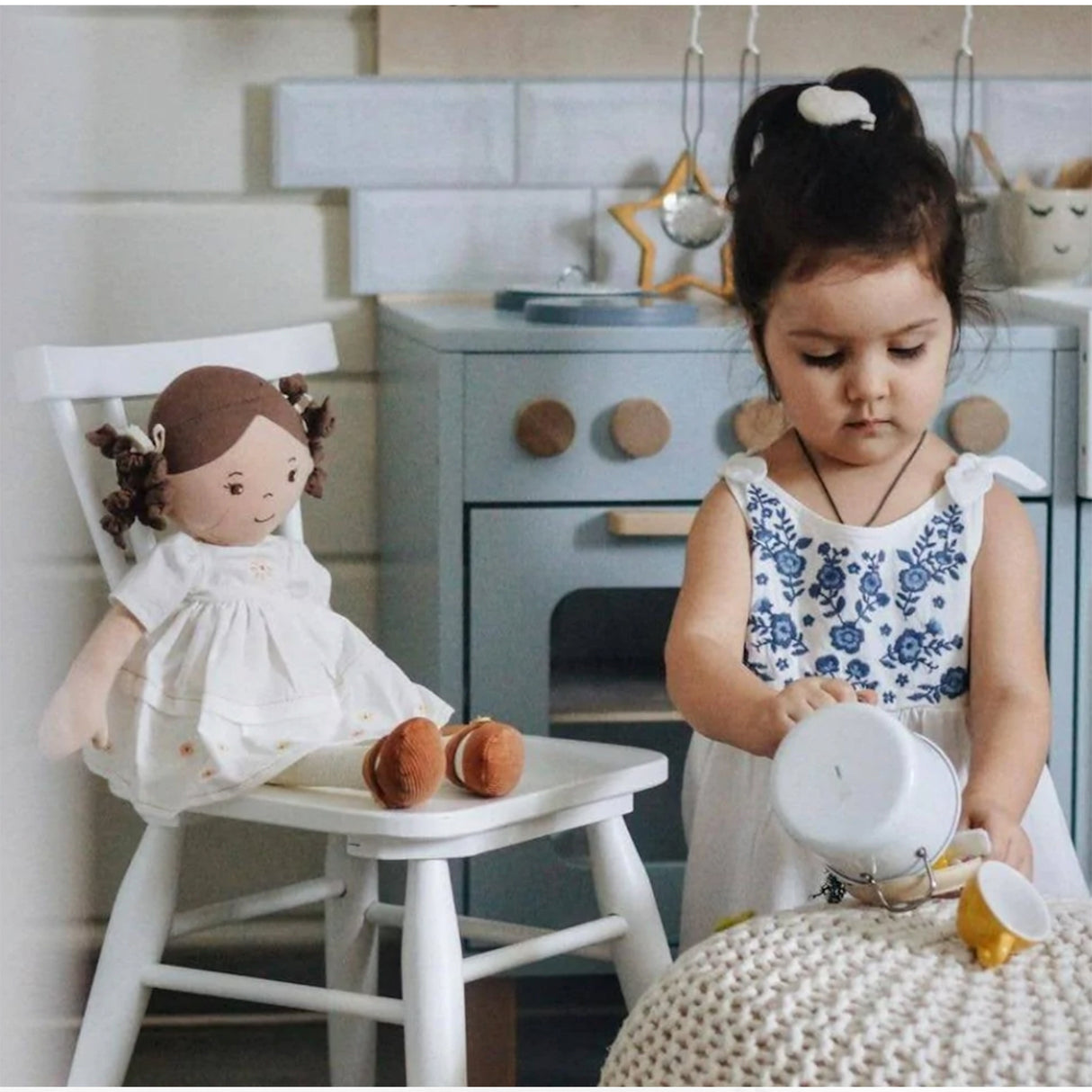 Child playing with a doll in a playroom kitchen setting