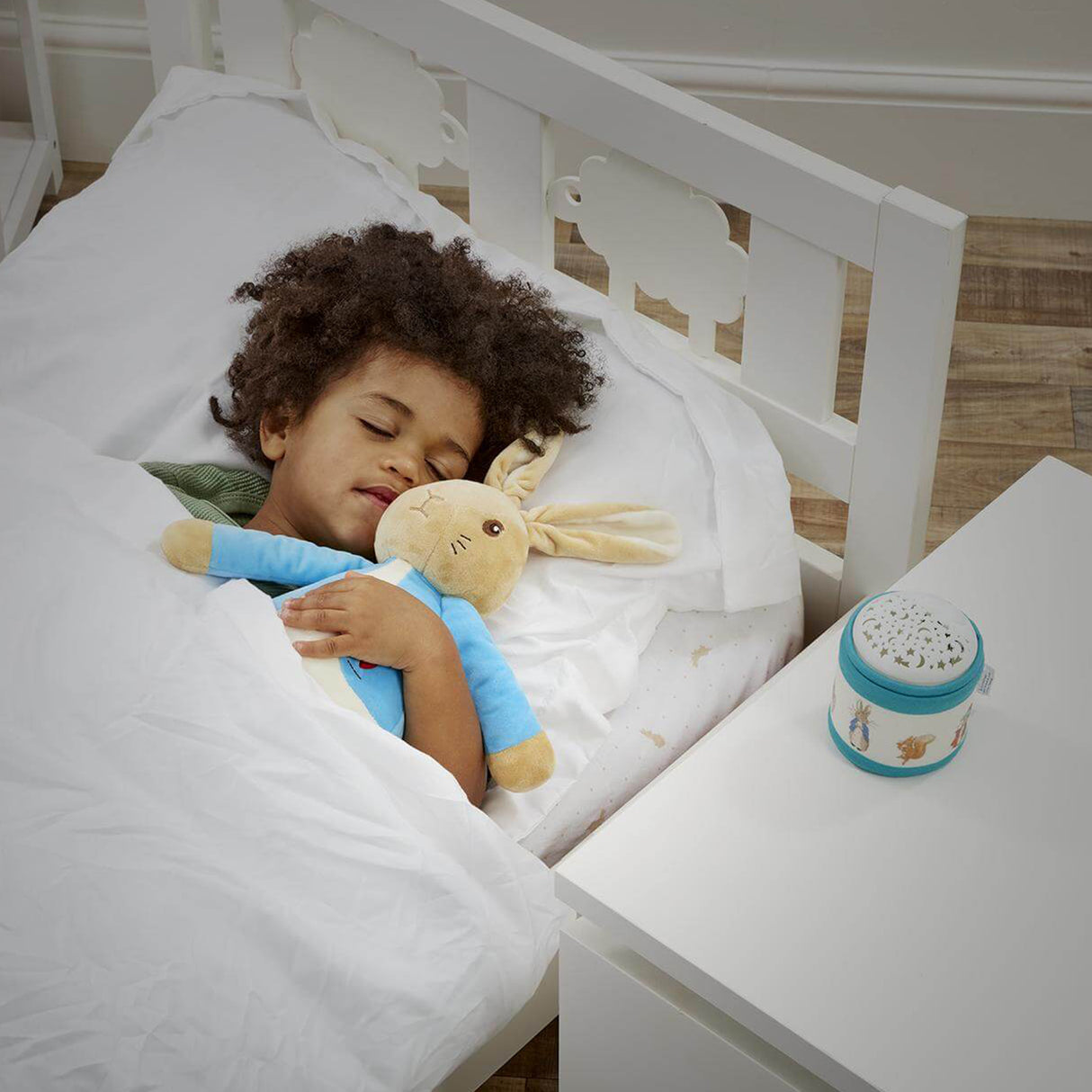 child sleeping with Peter Rabbit soft toy with a musical night light on the side