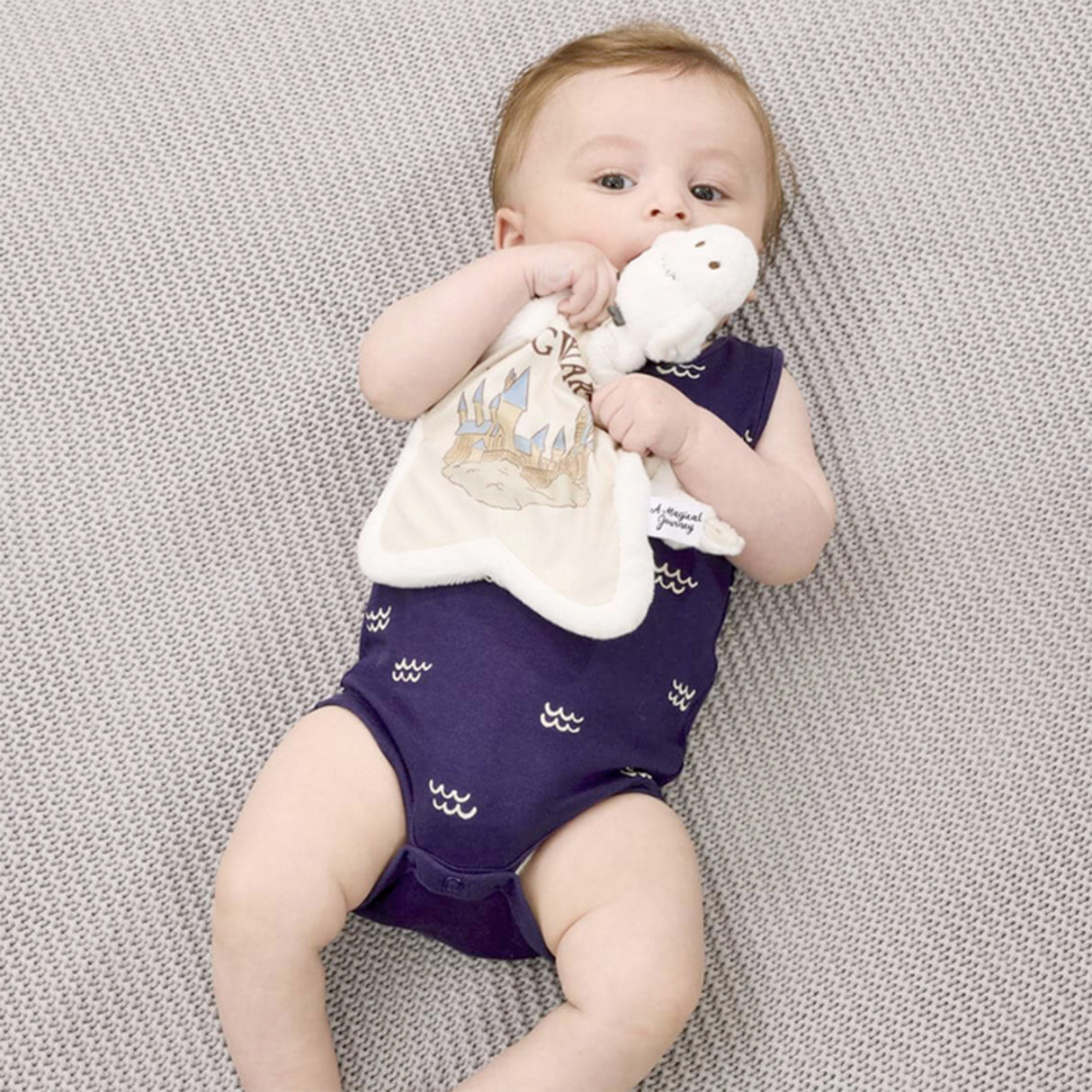 Hedwig Star-shaped soother with Baby lying on a textured surface