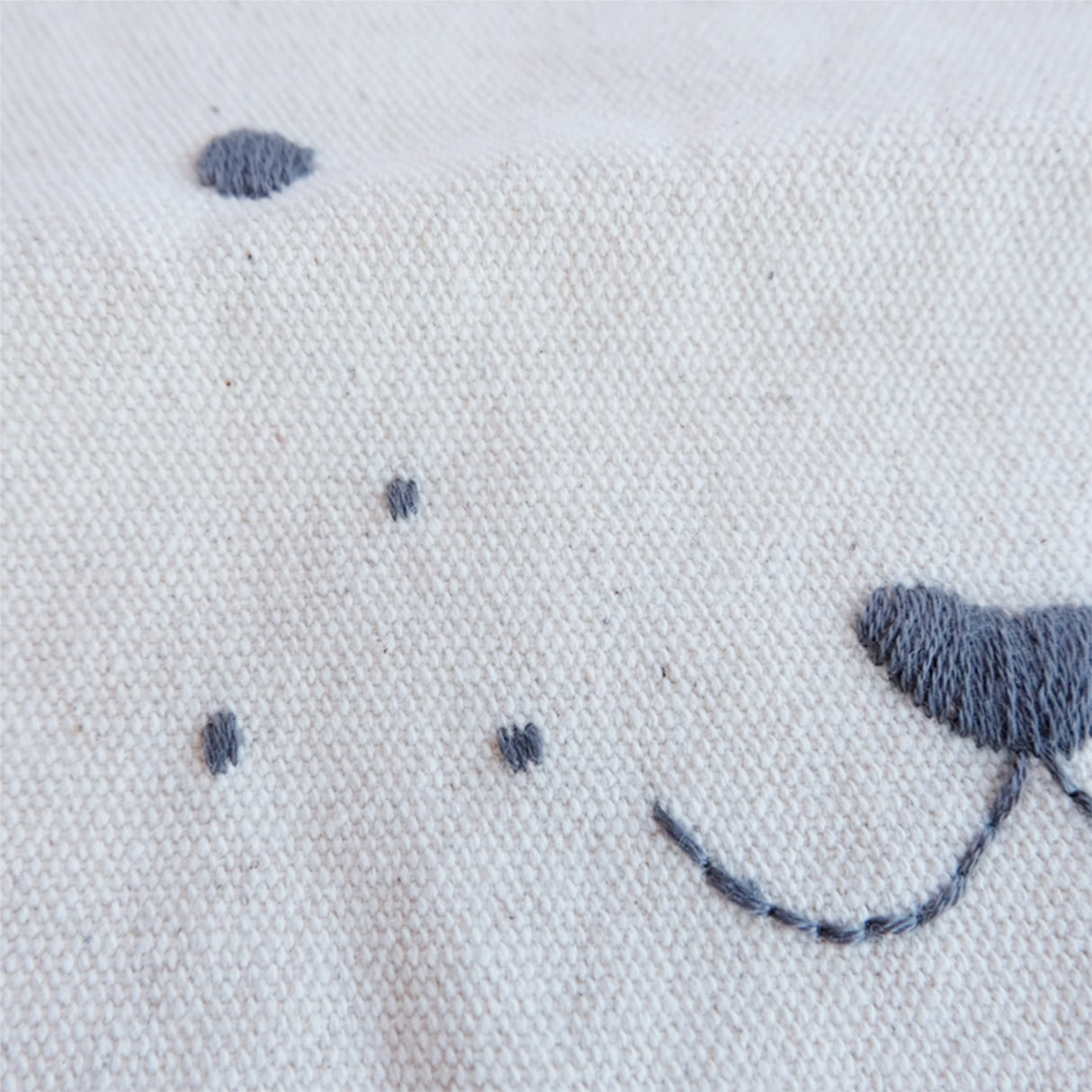 Embroidered design of a face on fabric with grey thread