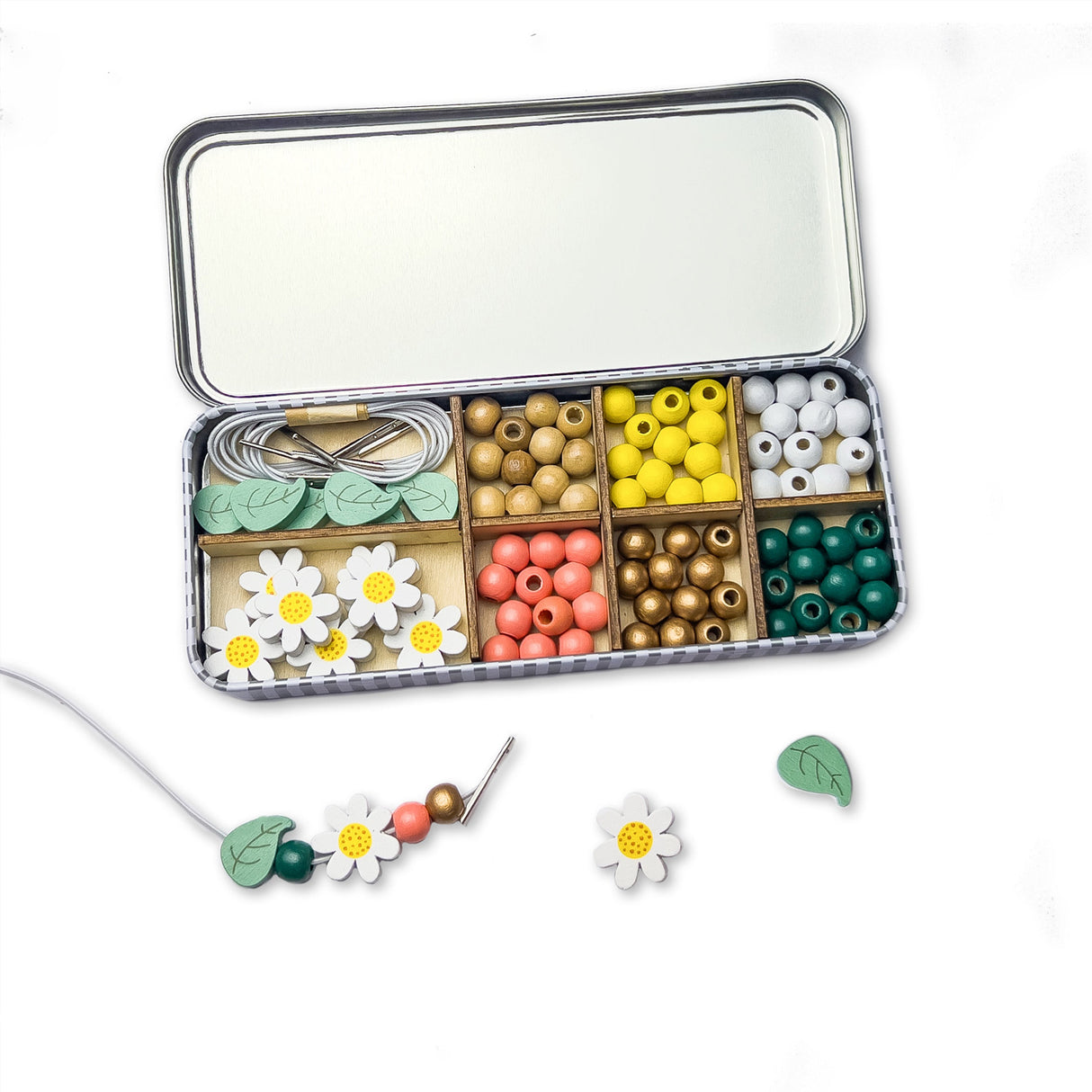 Colourful beads and floral elements in a divided tin on a white background