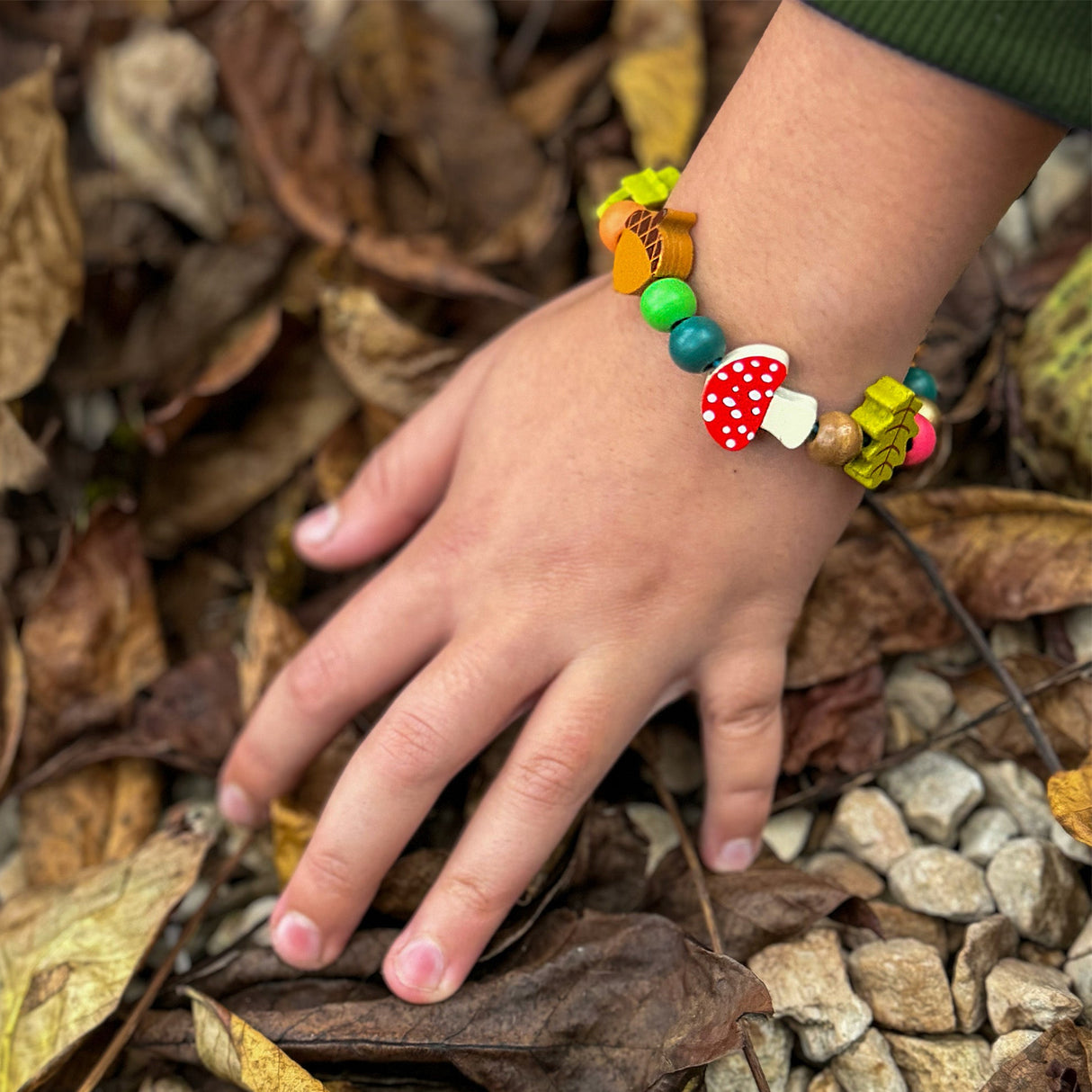 Colourful wooden beads on a childs hand touching leaves