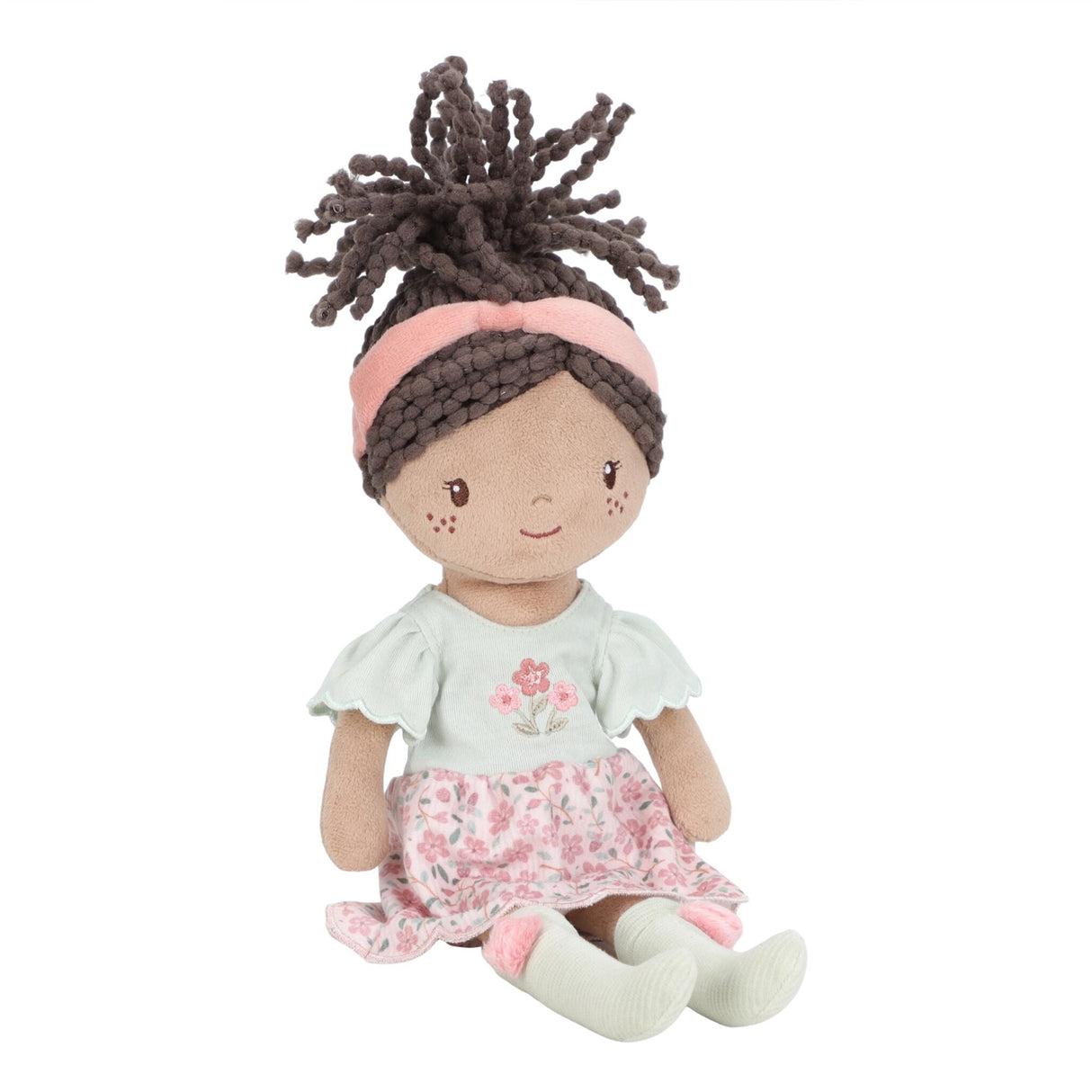 Soft doll with floral pink and sage green dress, pink headband and sage green socks with pink pompoms. Curly brown hair tied in a ponytail.