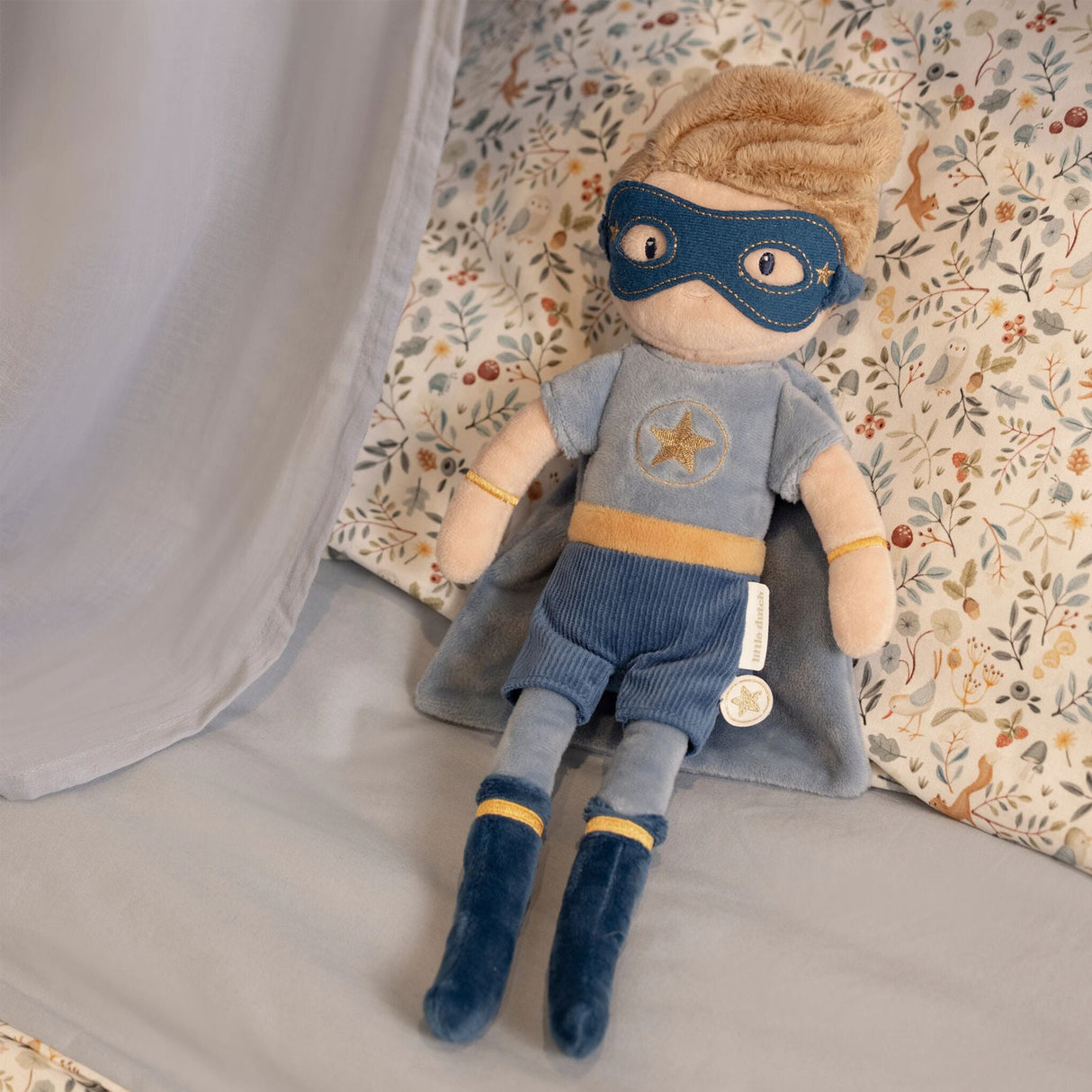 Toy superhero with cape and mask on a floral-patterned surface