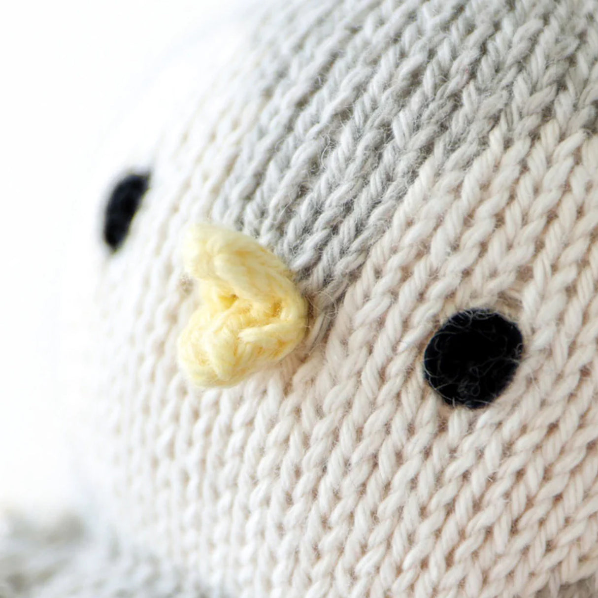 Close-up of a knitted penguin with a yellow beak and black dot eyes