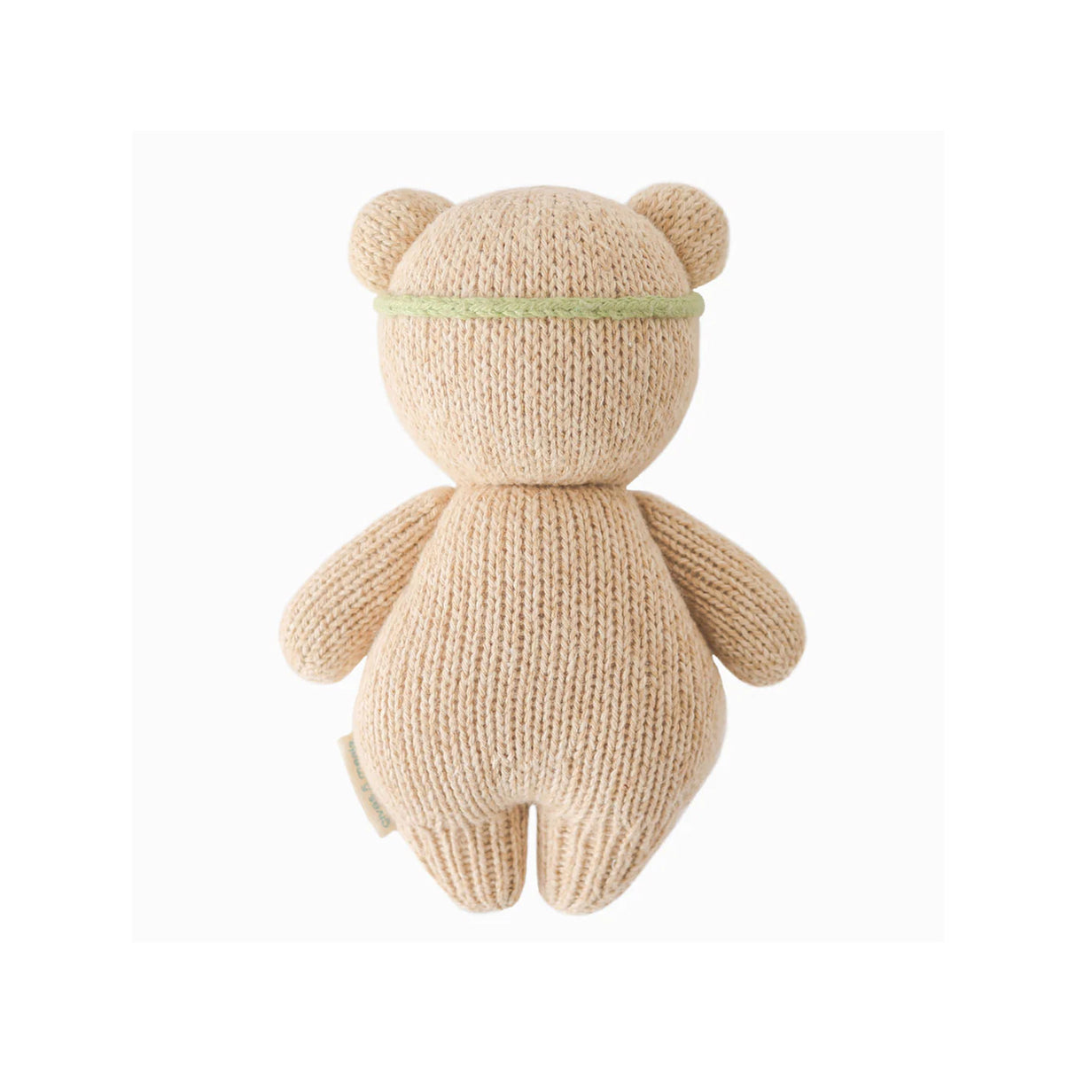 Knitted teddy bear with a green headband on a white background