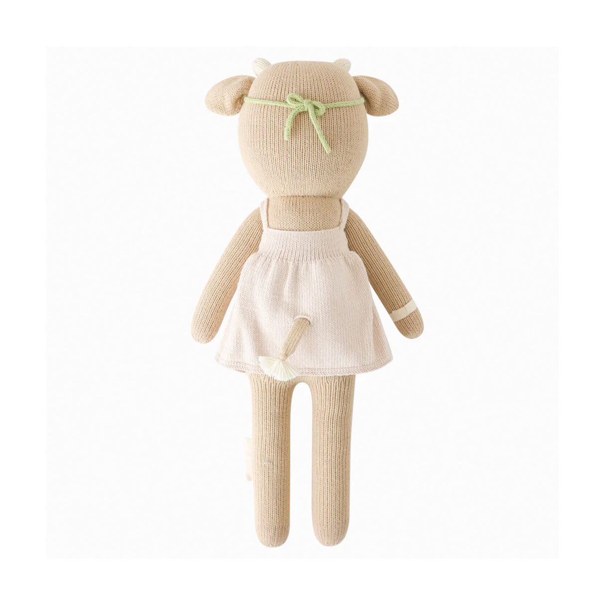 Knitted soft toy cow with a pale pink dress from behind on a white background