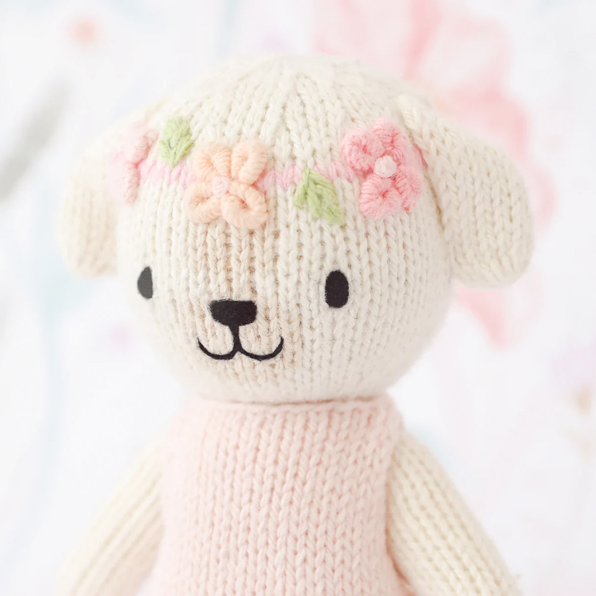 Knitted dog with floral headband on a light background
