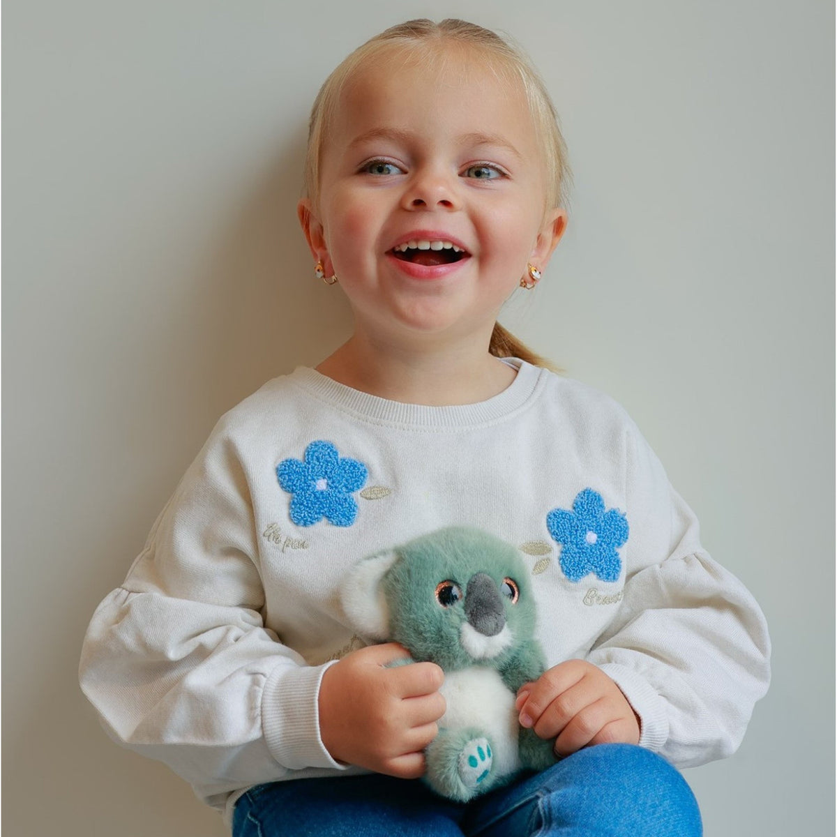 Young girl smiling and holding Gipsy Toys Cutydoos Koala small plush soft toy