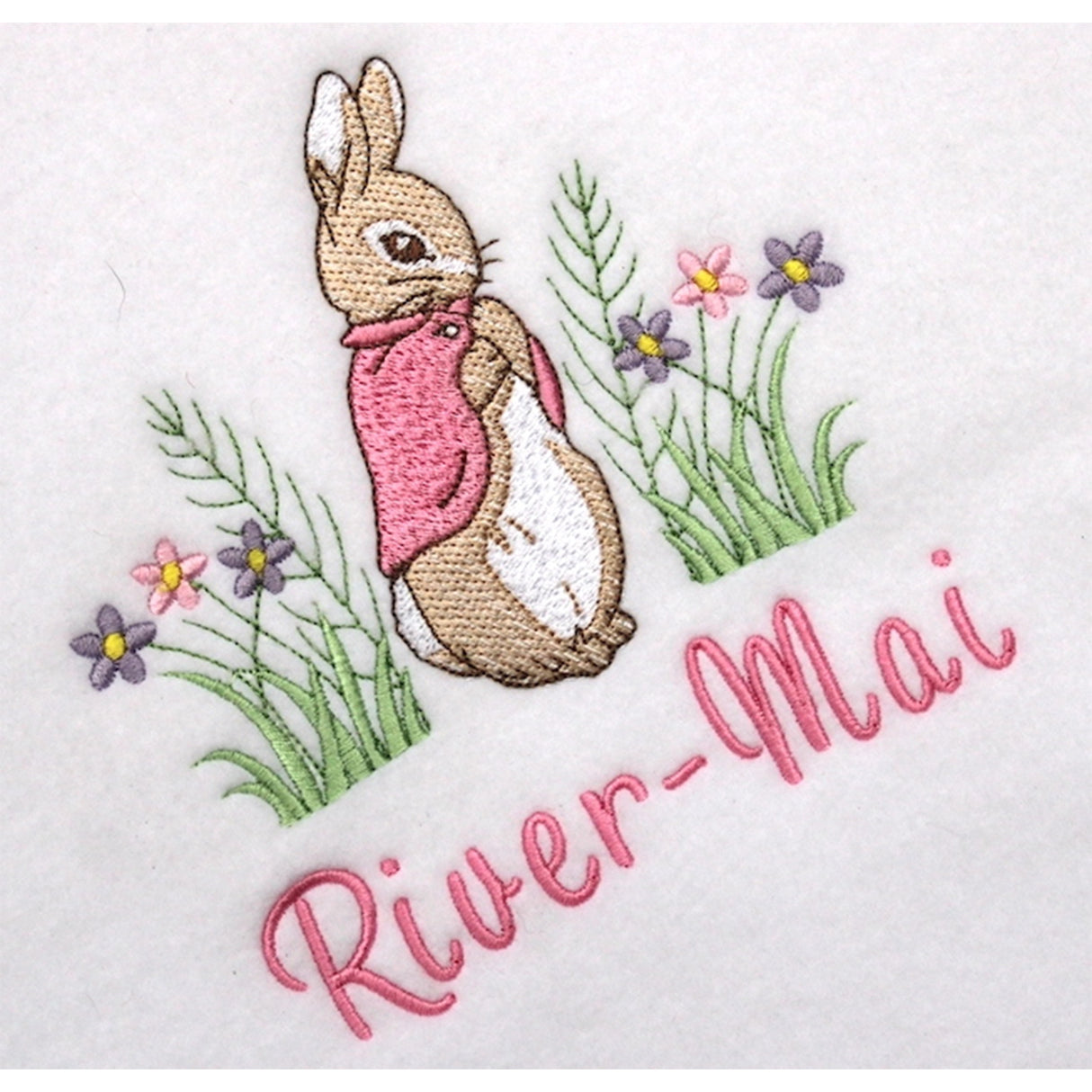 Embroidered design of a Flopsy bunny rabbit with flowers and the name 'River-Mai' on a white background