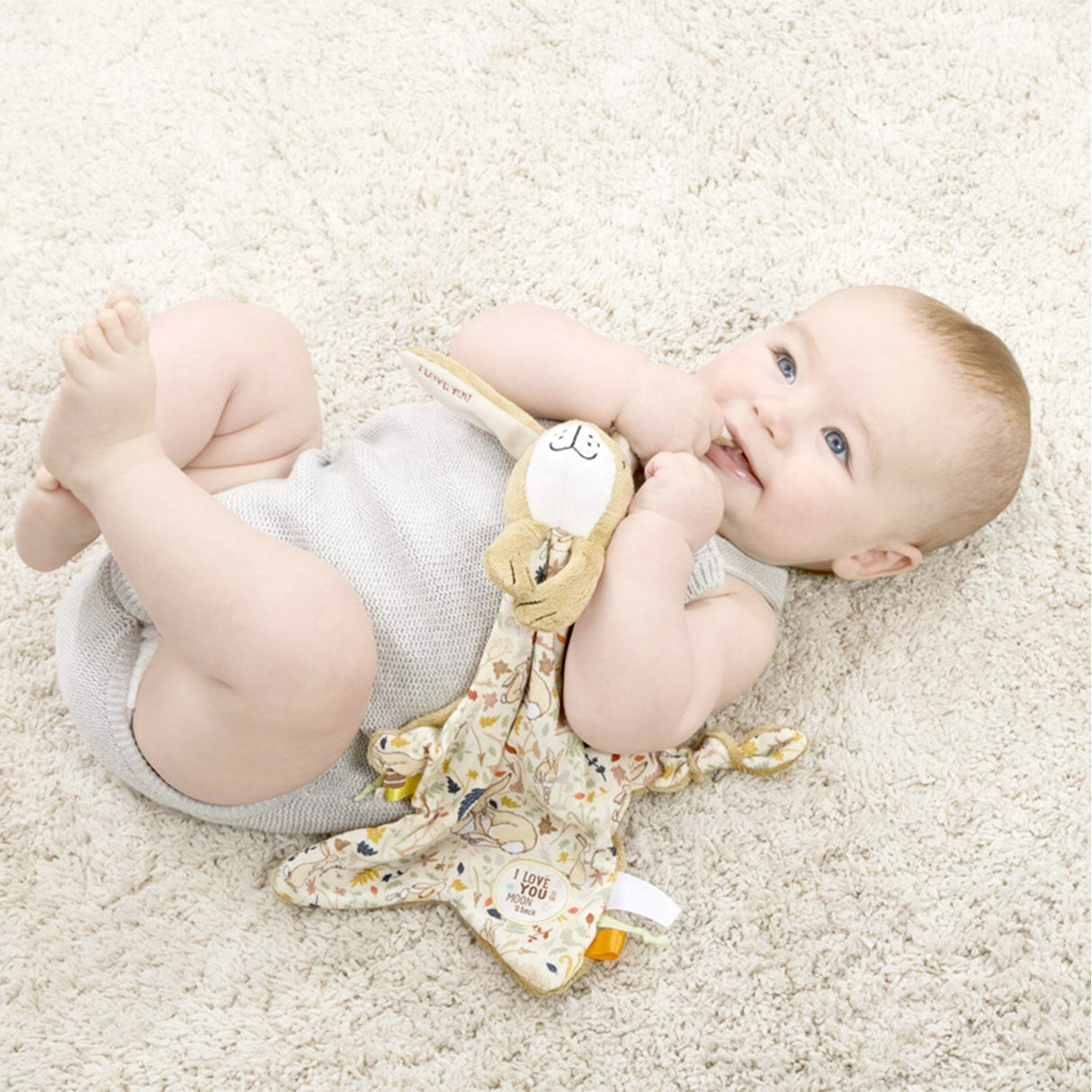 Baby lying on awith Nutbrown Hare Star-shaped baby comforter with bunny soft toy, attachment and tags