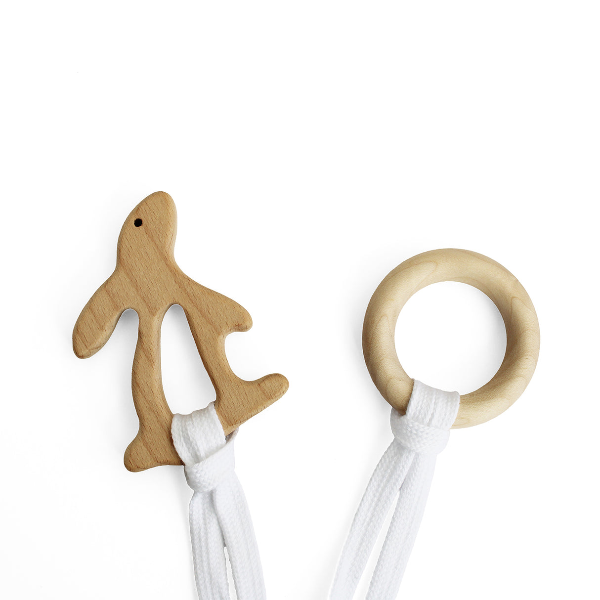 Wooden rabbit-shaped teether and round teething ring with white strings on a white background