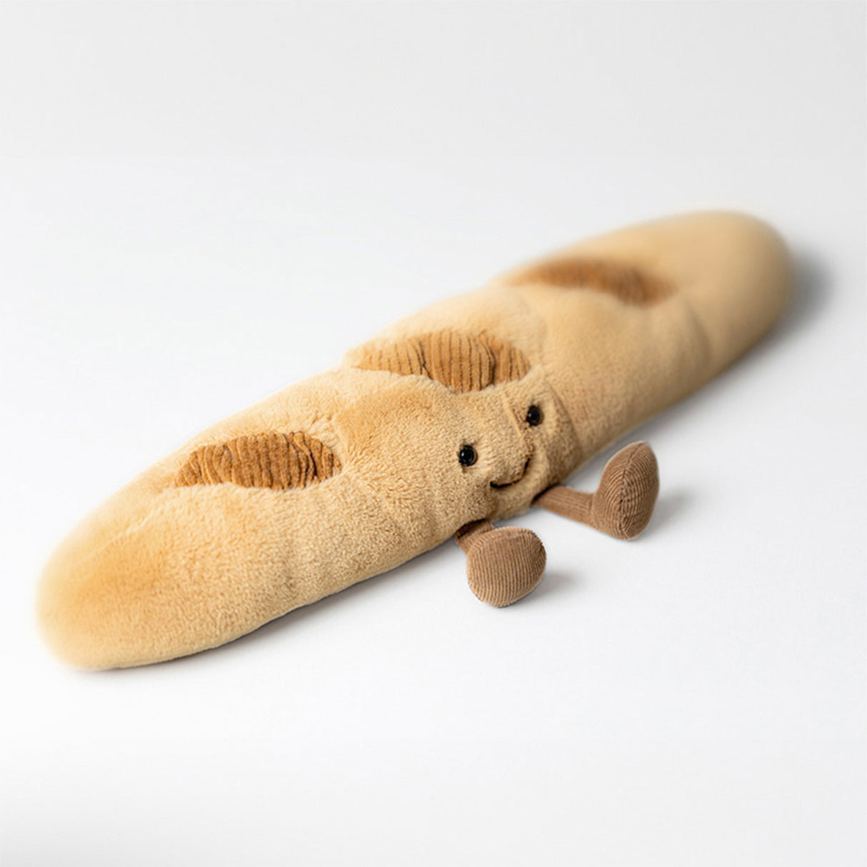 Plush toy shaped like a baguette with a face on a white background