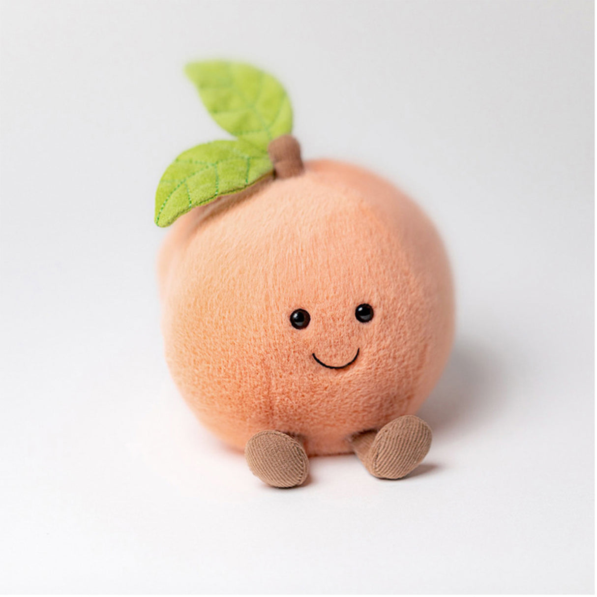 Jellycat amuseable Plush toy peach with a smiling face on a white background