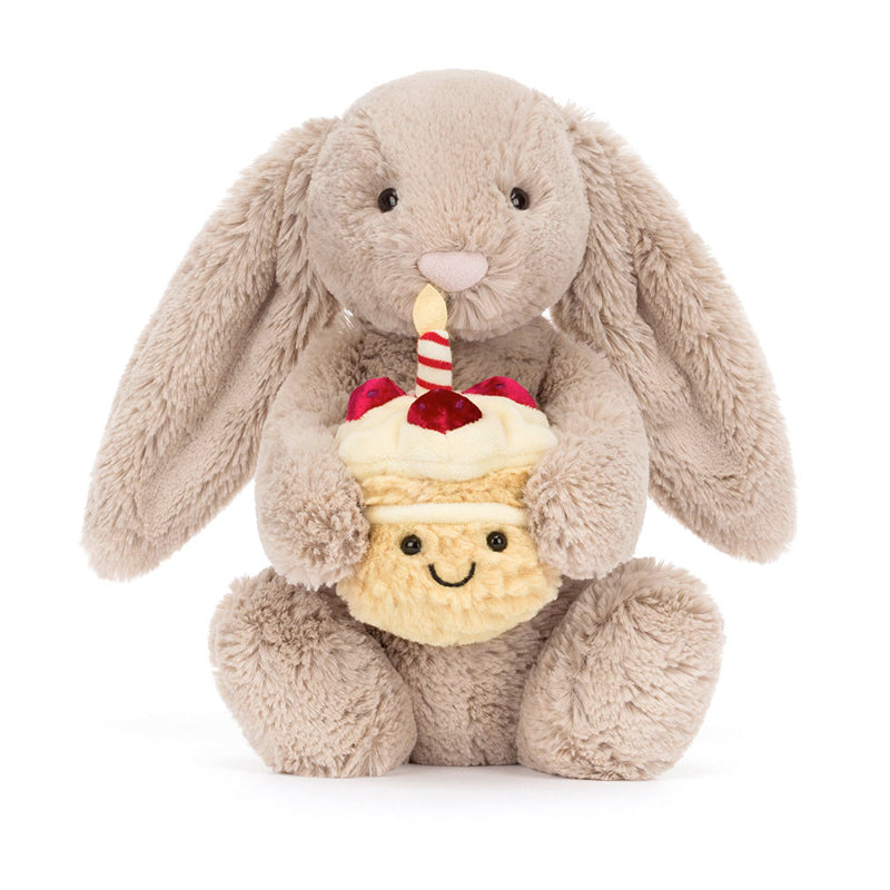 A beige plush toy rabbit sitting upright holding a birthday cake with a single candle on top.