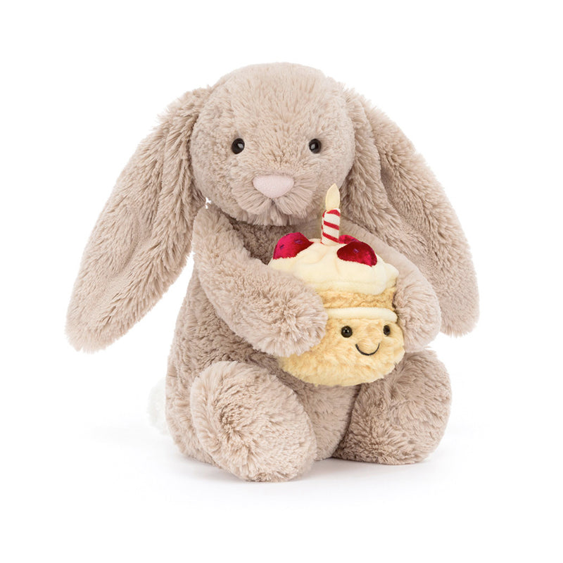 A beige plush toy rabbit sitting upright holding a birthday cake with a single candle on top.