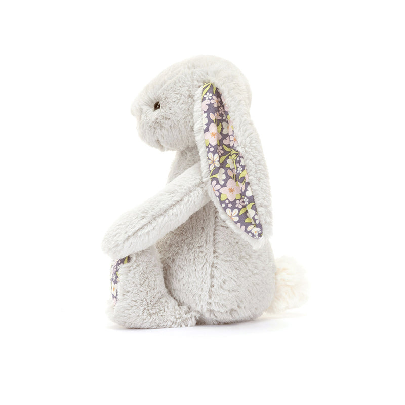 A small plush toy resembling a gray bunny with floral patterns on its ears and feet, and a white backdrop.