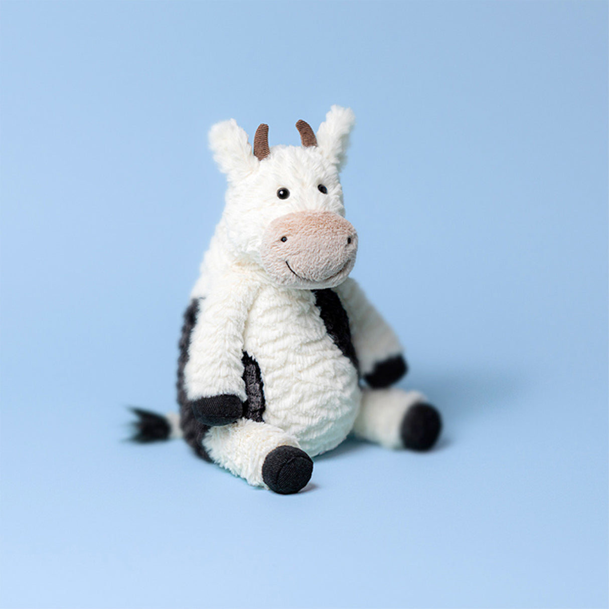 Plush cow soft toy on a light blue background