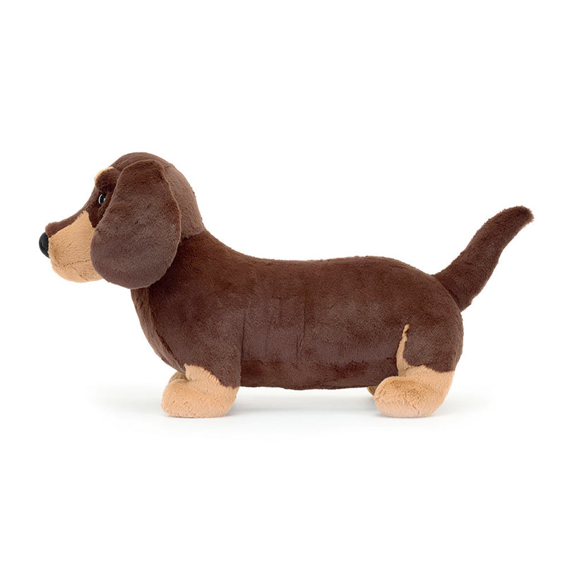 A plush toy resembling a small sausage dog with dark brown fur and light brown patches, featuring waggly ears and a perky tail.