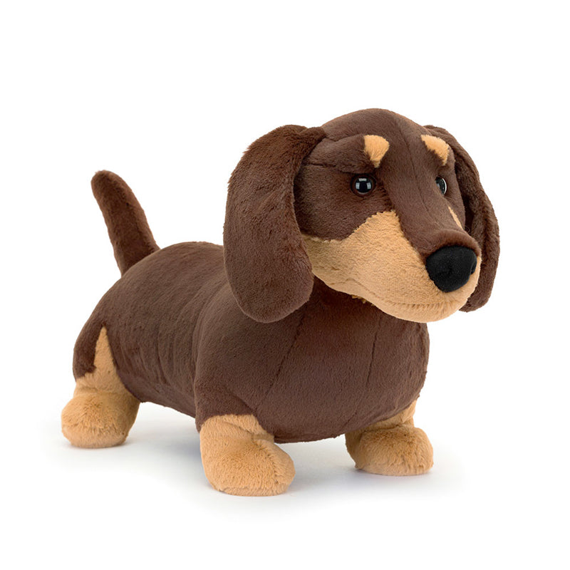 A plush toy resembling a small sausage dog with dark brown fur and light brown patches, featuring waggly ears and a perky tail.