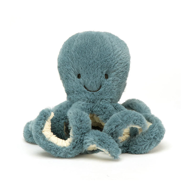 A soft toy resembling an octopus with a smiling face, in teal color with white and darker teal tentacles, and a scruffled cream fur texture.