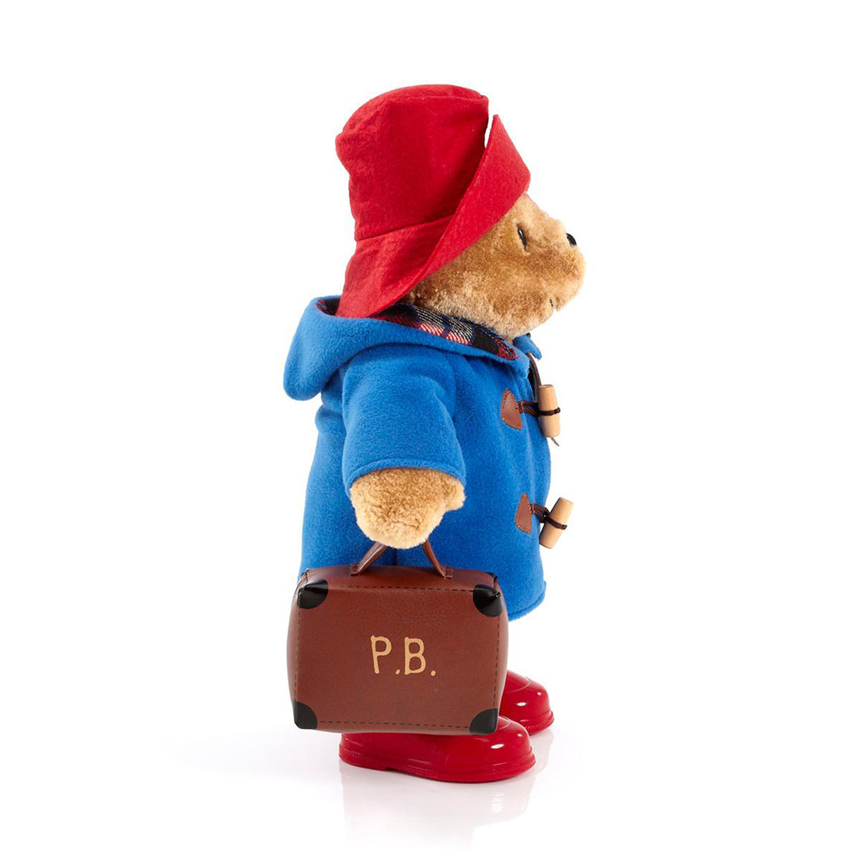 Stuffed toy bear in a blue coat and red hat with a suitcase on a white background
