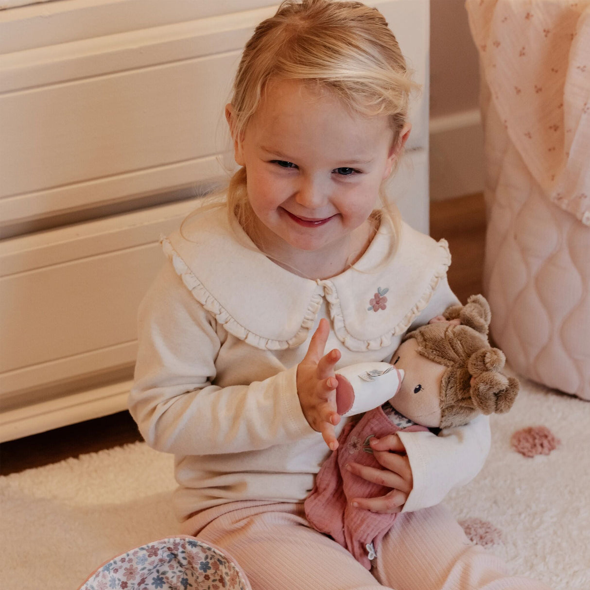 Child holding a soft doll toy in a cozy indoor setting