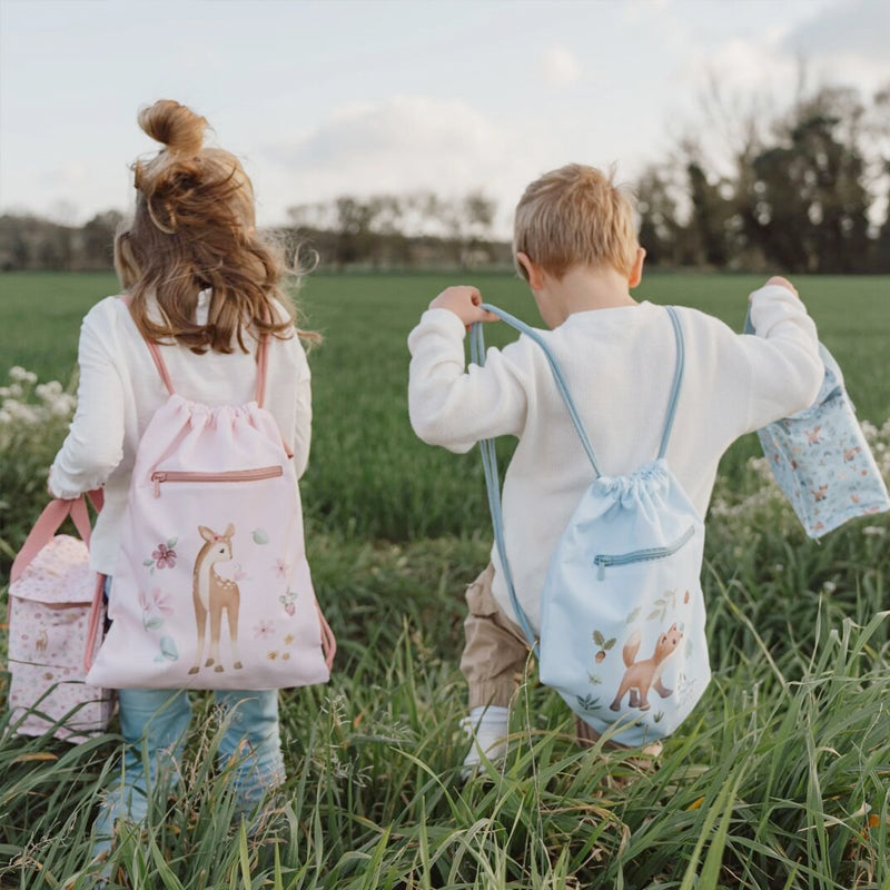 Two children with little dutch drawstring bags in a field