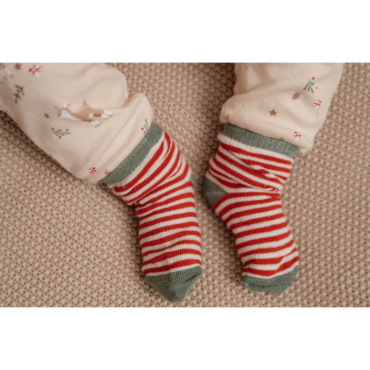 Red and white striped socks on a child's feet with a beige background