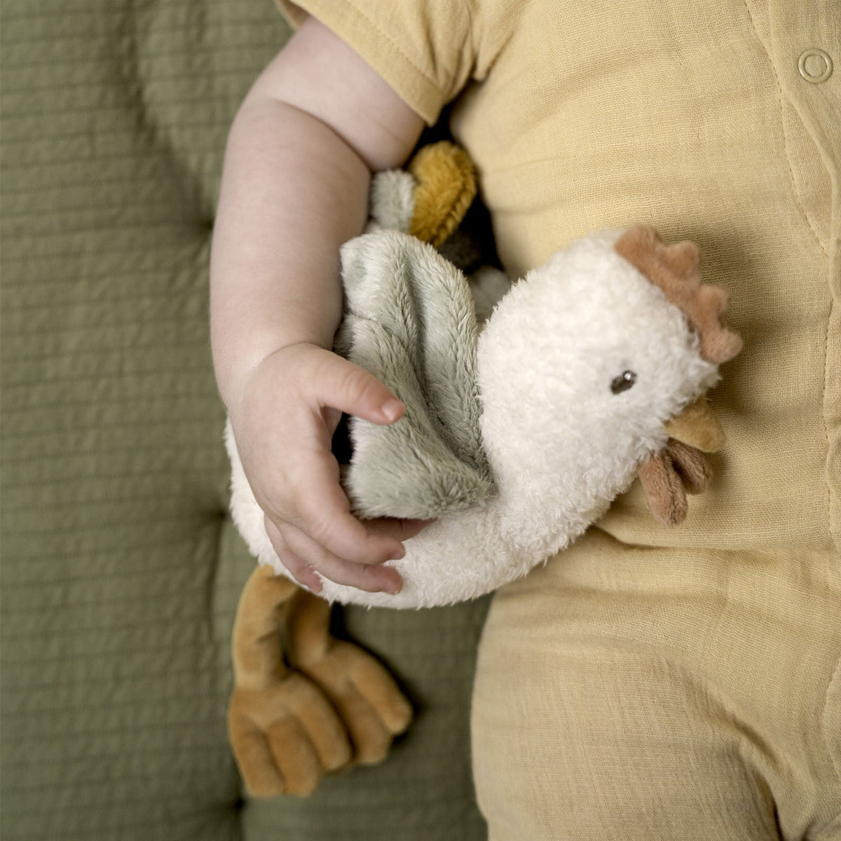 A close-up of a baby's hand holding a Little Dutch Cuddle Chicken soft toy