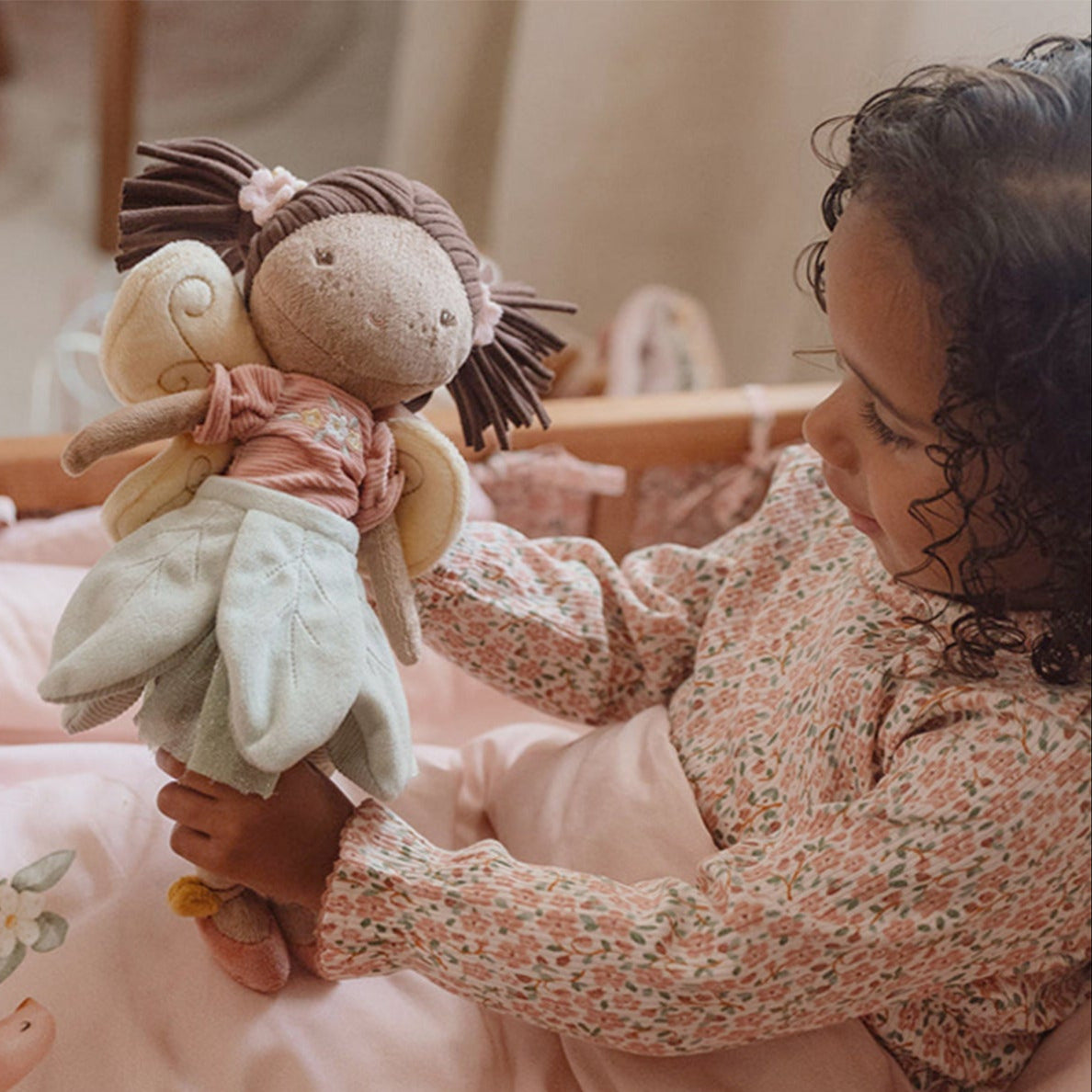 Child holding a plush fairy doll toy in a cozy bedroom setting