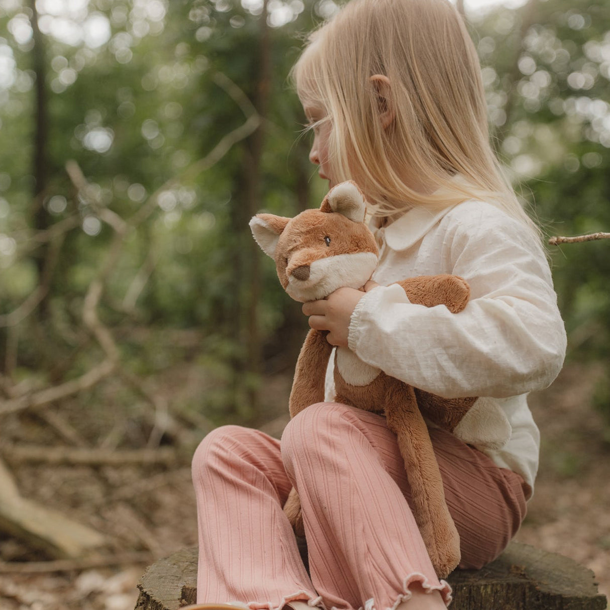 Child holding a tfox toy in a forest setting