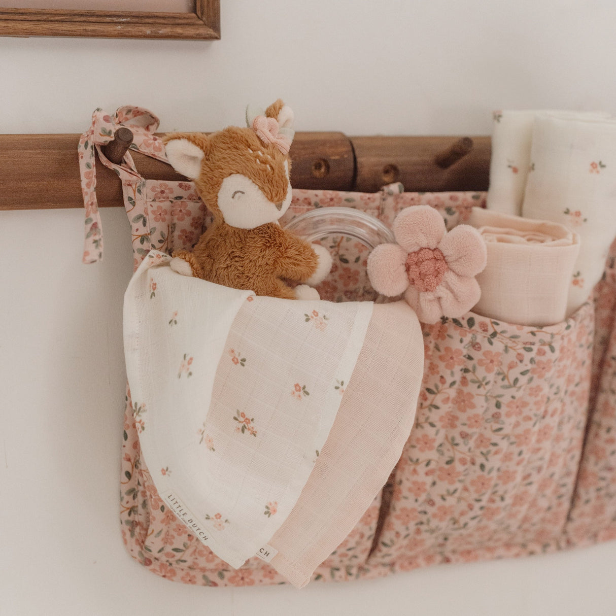 Floral-patterned basket with a plush toy and decorative items on a white surface.