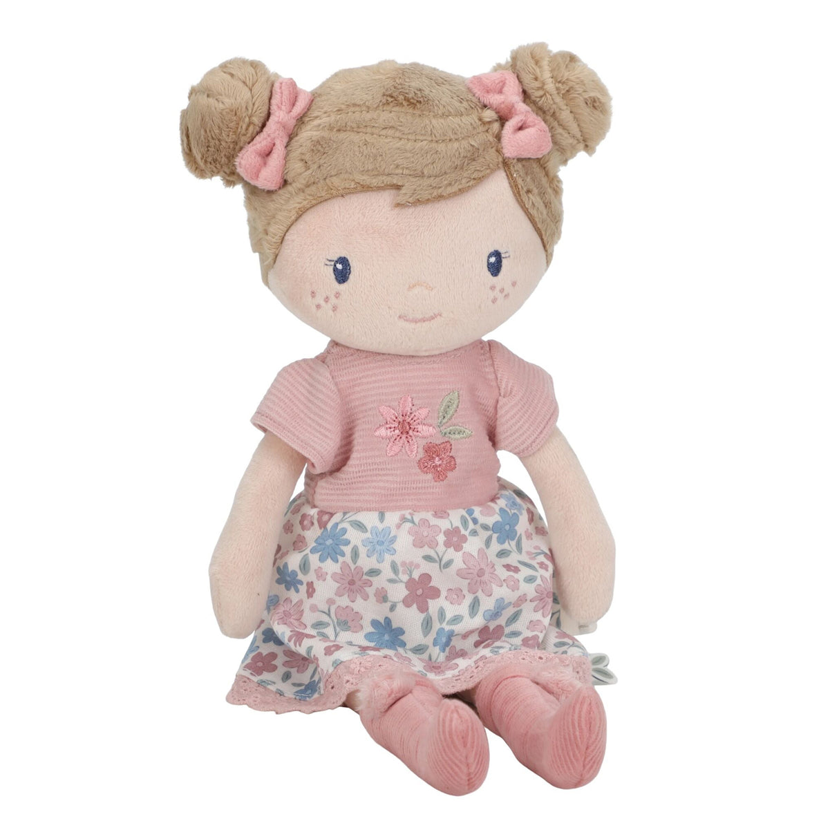 Little Dutch Hug Doll Rosa sitting, showing soft brown bun hair with pink bows, embroidered pink T-shirt and blue and pink floral skirt, on a white background