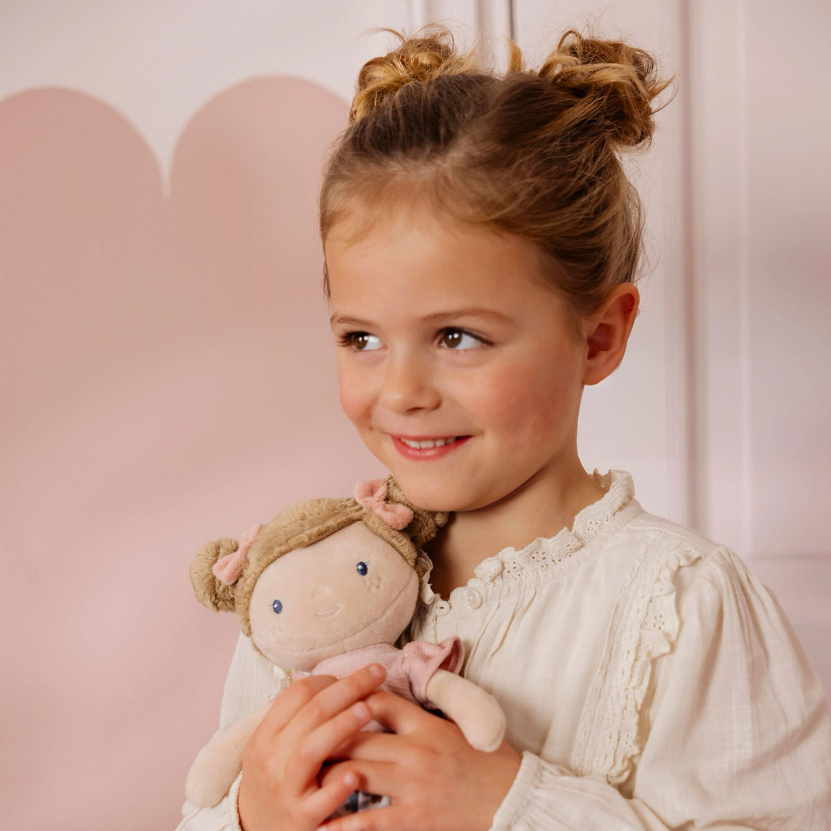Little Dutch Hug Doll Rosa sitting on a surface, full body view showing floral outfit and pompom boots