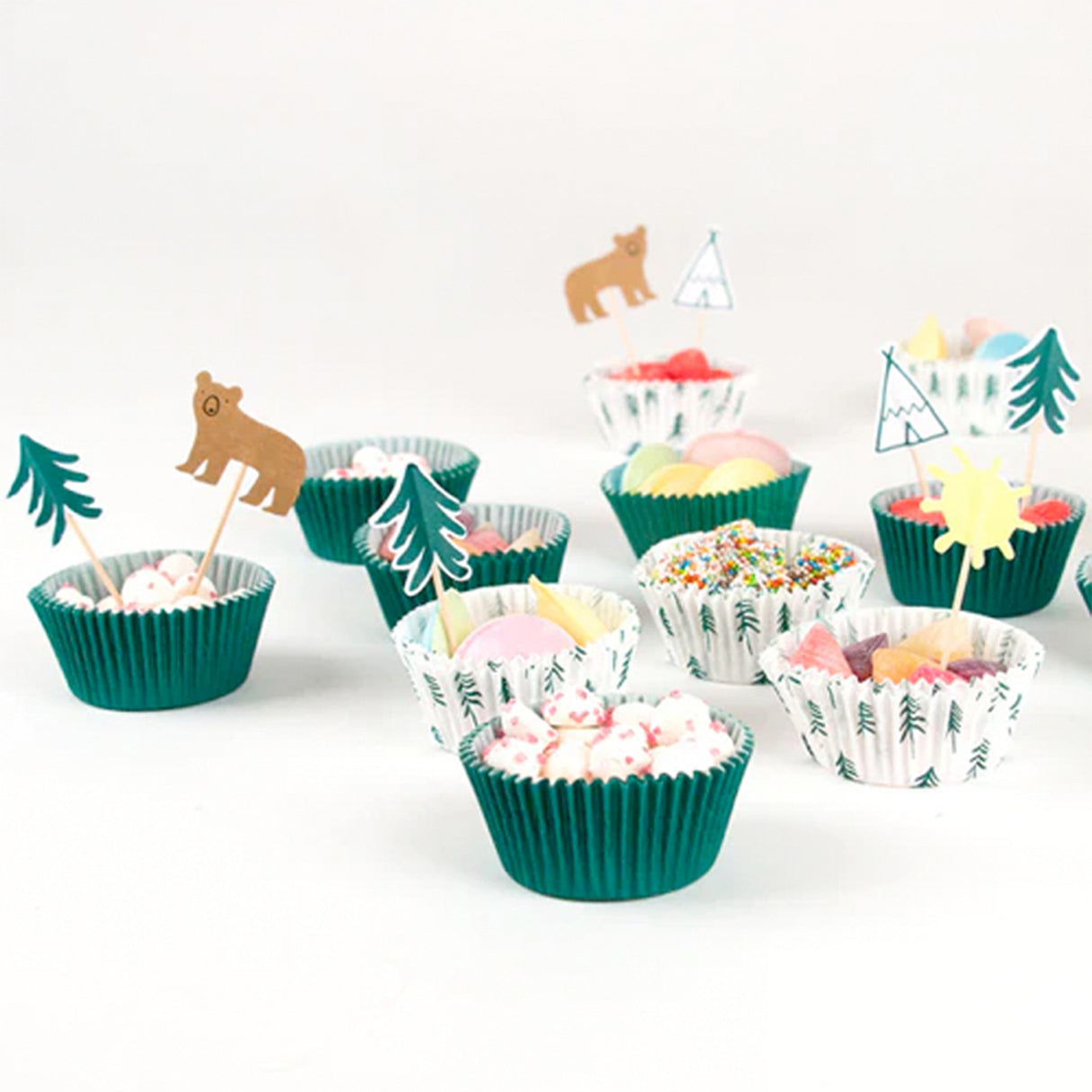 Cupcakes with green wrappers and animal-themed toppers on a white background