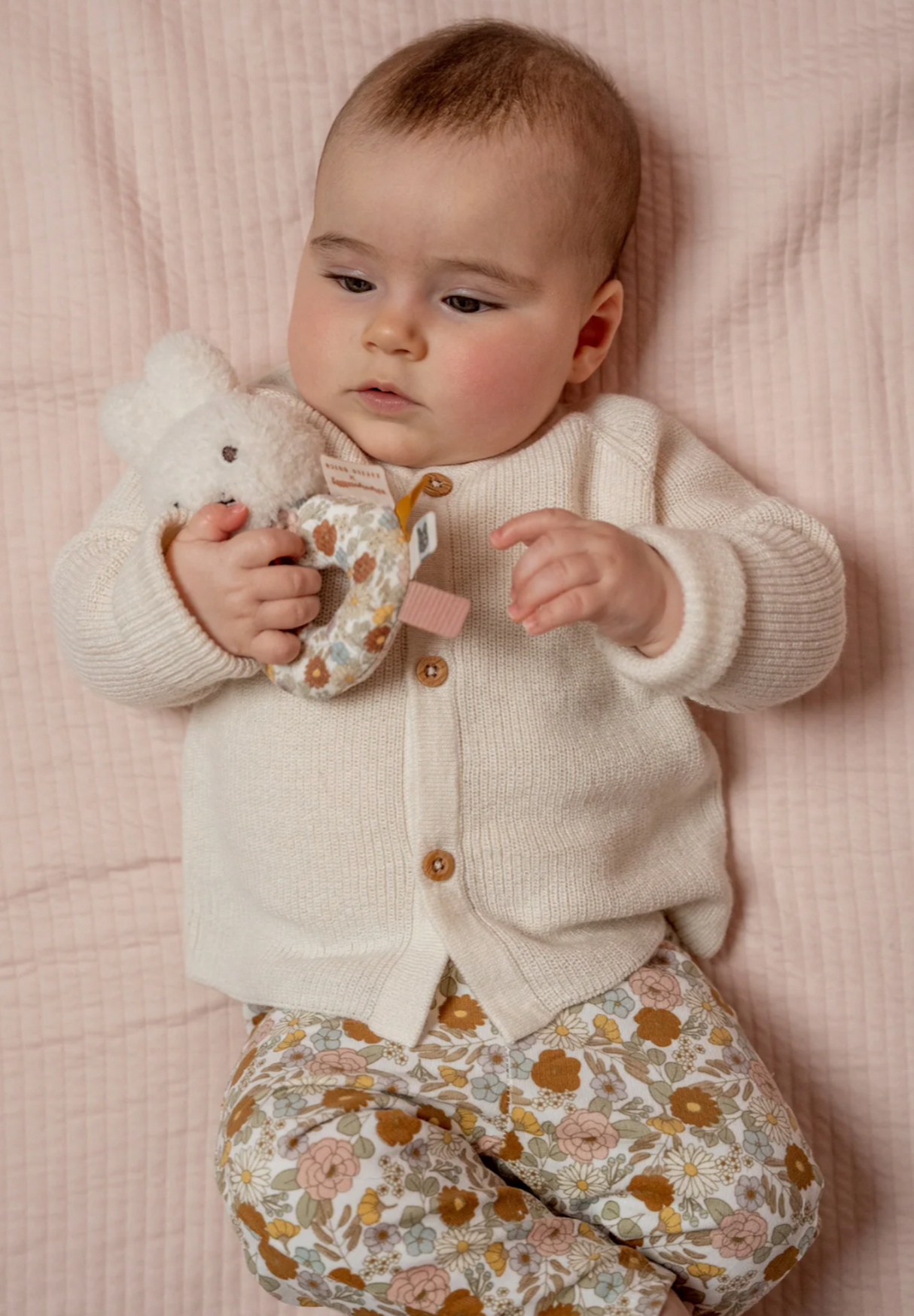 Baby lying on pink blanket holding Little Dutch Miffy Vintage Flowers ring rattle