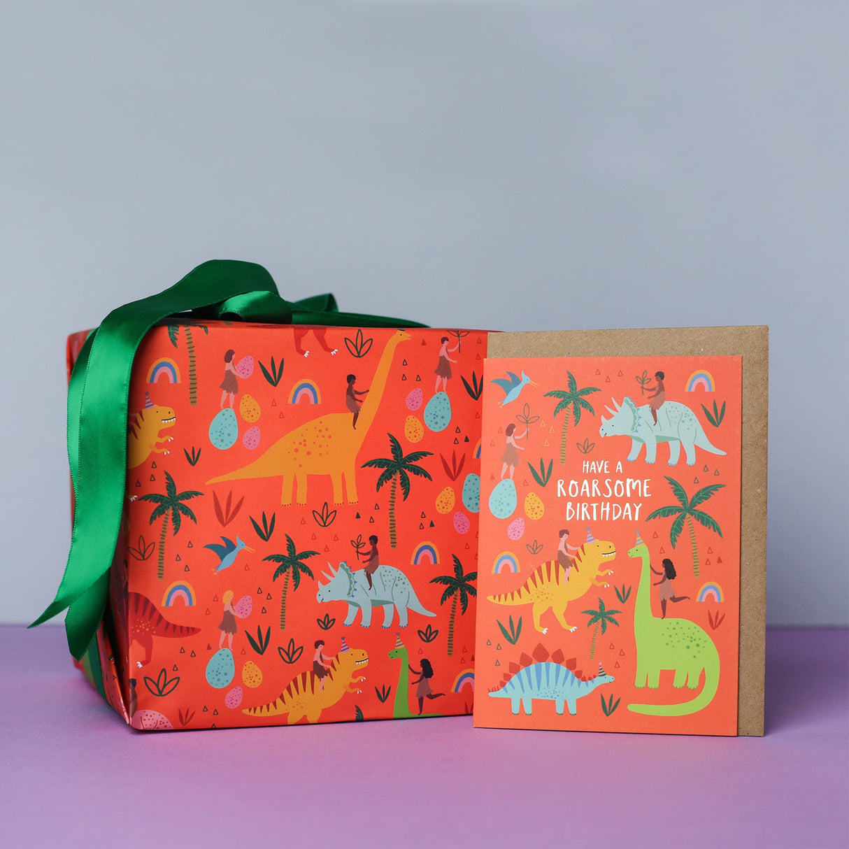 Gift box with dinosaur pattern and matching card on a purple surface