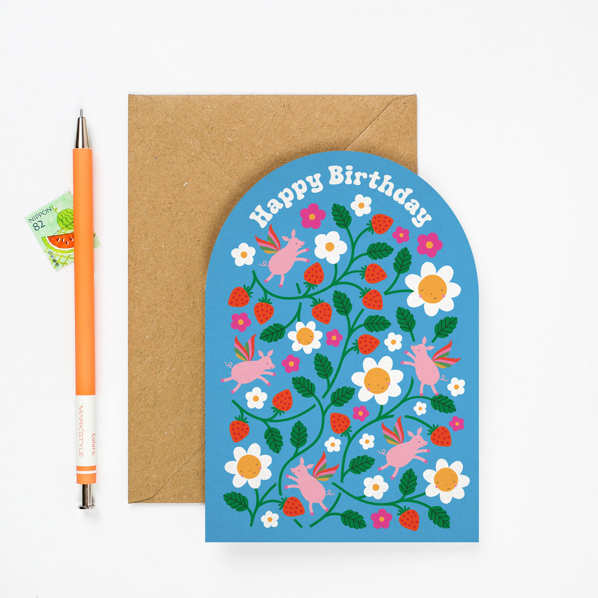 Greeting card with floral design and 'Happy Birthday' text, accompanied by a pen and envelope on a white background.