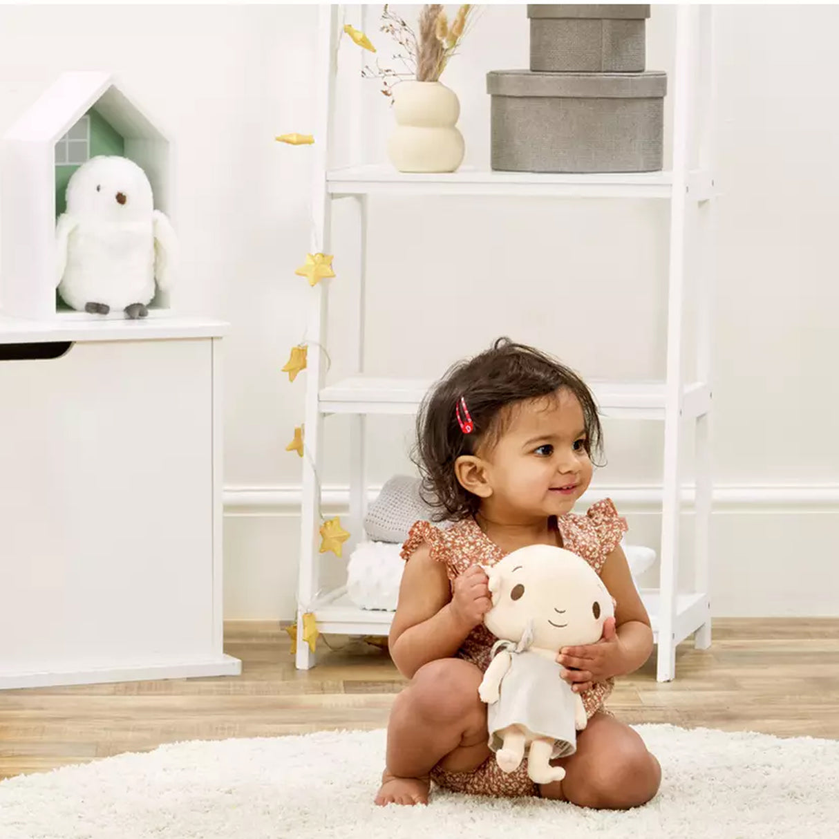 Child holding a plush harry potter dobby soft toy in a room with shelves and decor