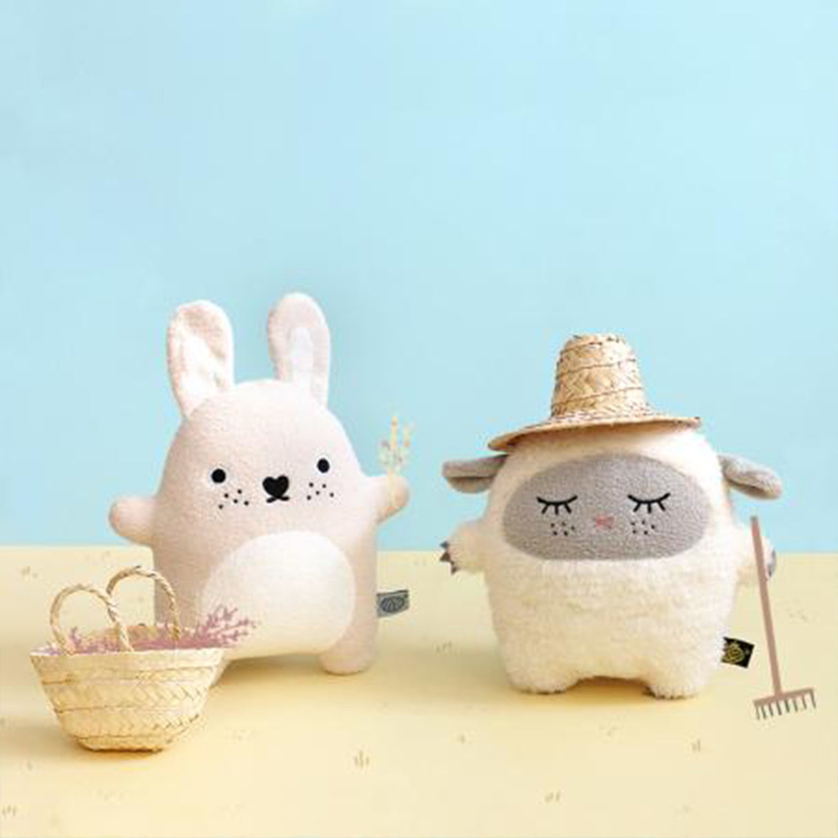 Two plush toys, a rabbit and a sheep, on a yellow surface with a light blue background.