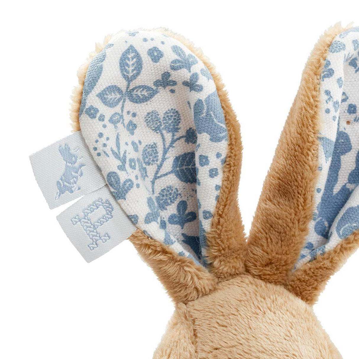 Close-up of a plush bunny toy with floral ears and tags on a white background