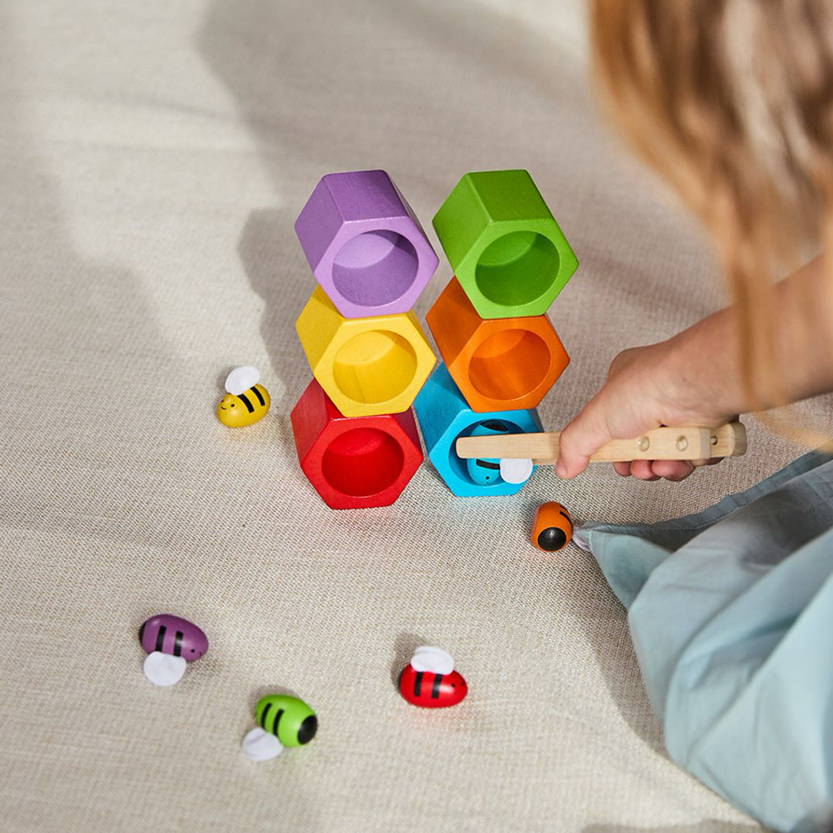 Child playing with colour matching bees and hive toy puzzle