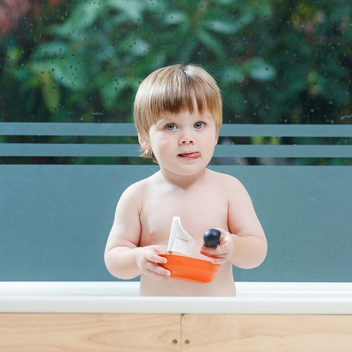 Child playing with a toy boat in a bathtub outdoors