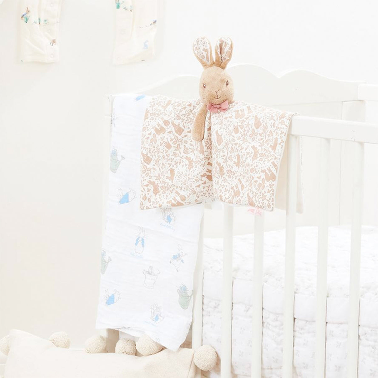 Baby crib with a flora Flopsy bunnyl blanket and plush toy in a bright room